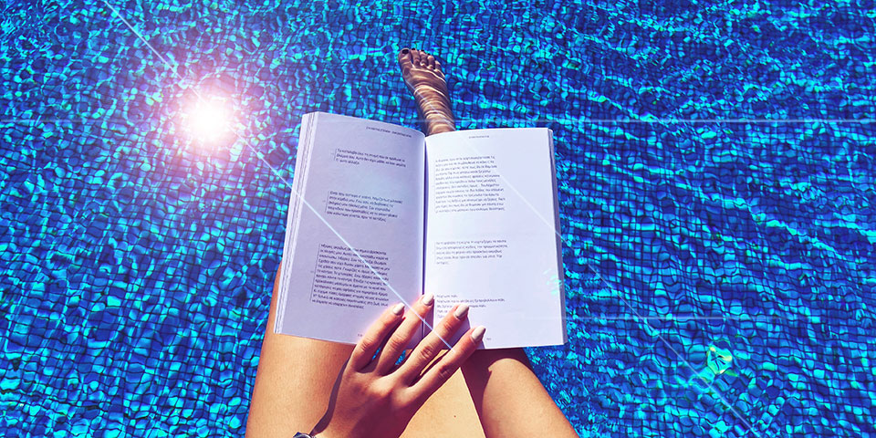 Επισκέπτης που χαλαρώνει με ένα βιβλίο δίπλα στην πισίνα